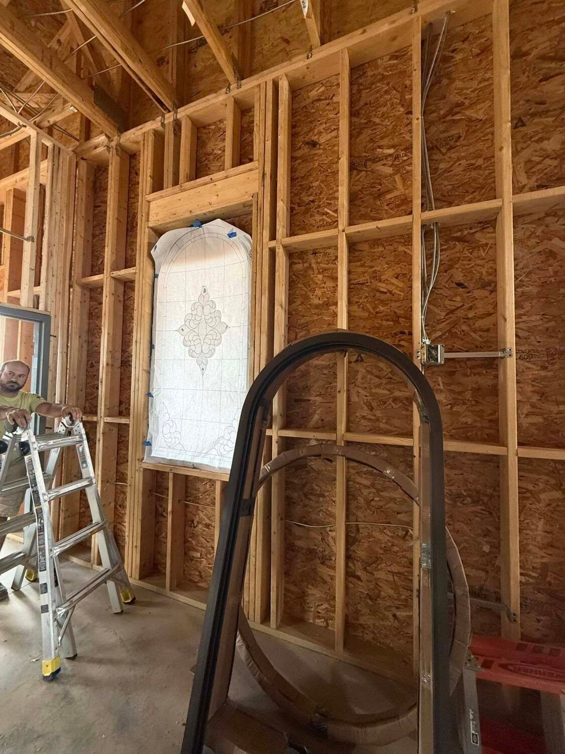 Interior view of a building under construction, showing wooden framing and a ladder.