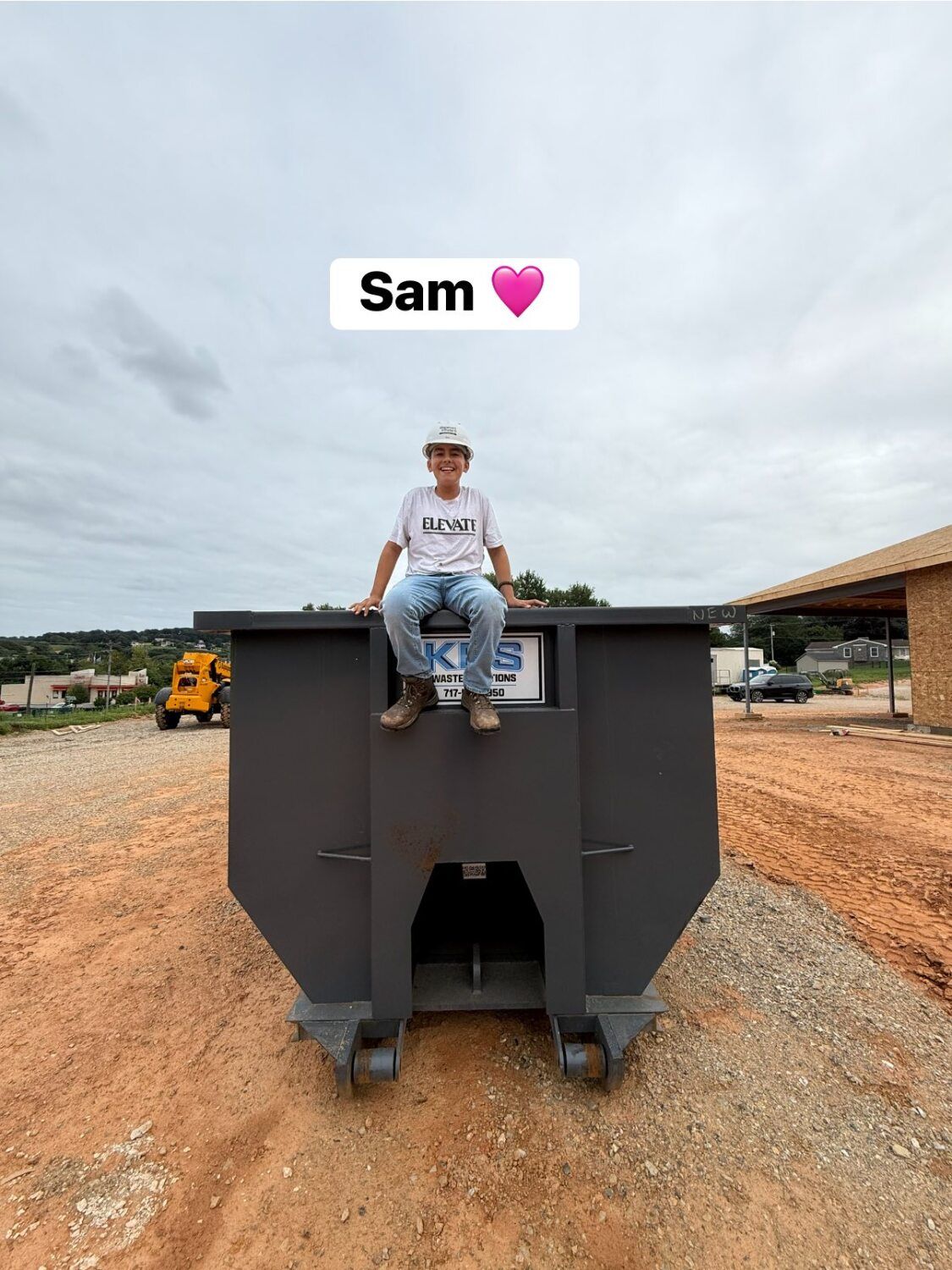 Person sits on top of a gray dumpster on a construction site; Sam, a person, with a pink heart, is written above.