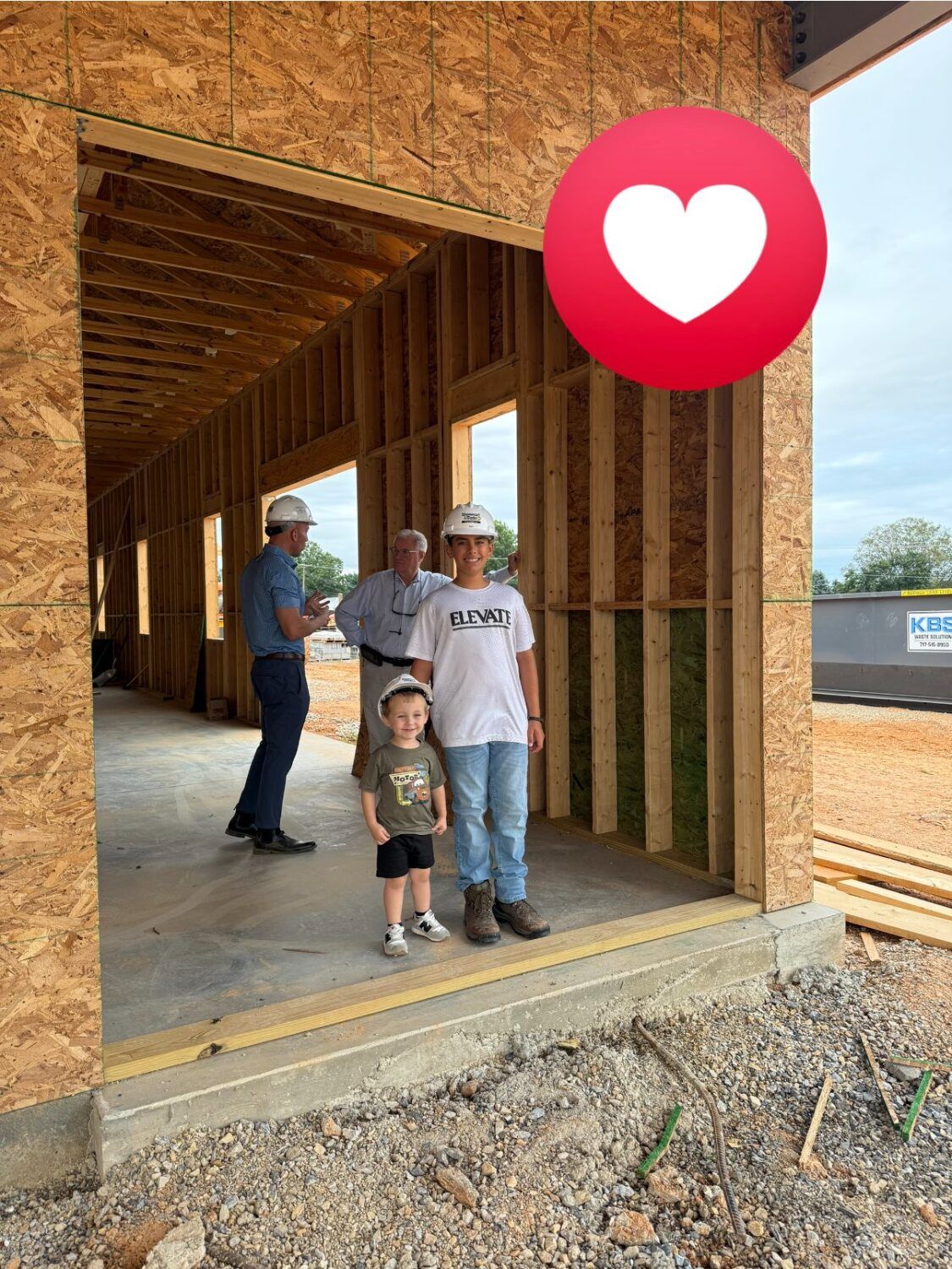 People in hard hats inside a building under construction. A heart emoji is in the upper right.