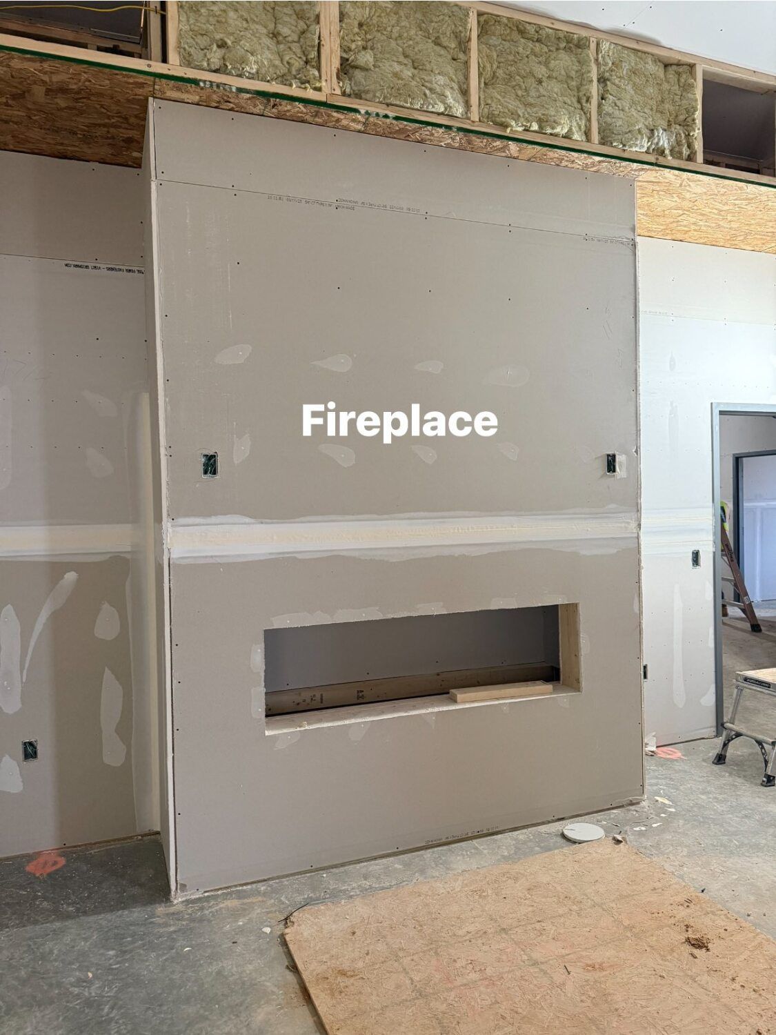 Drywall fireplace structure under construction in a room.
