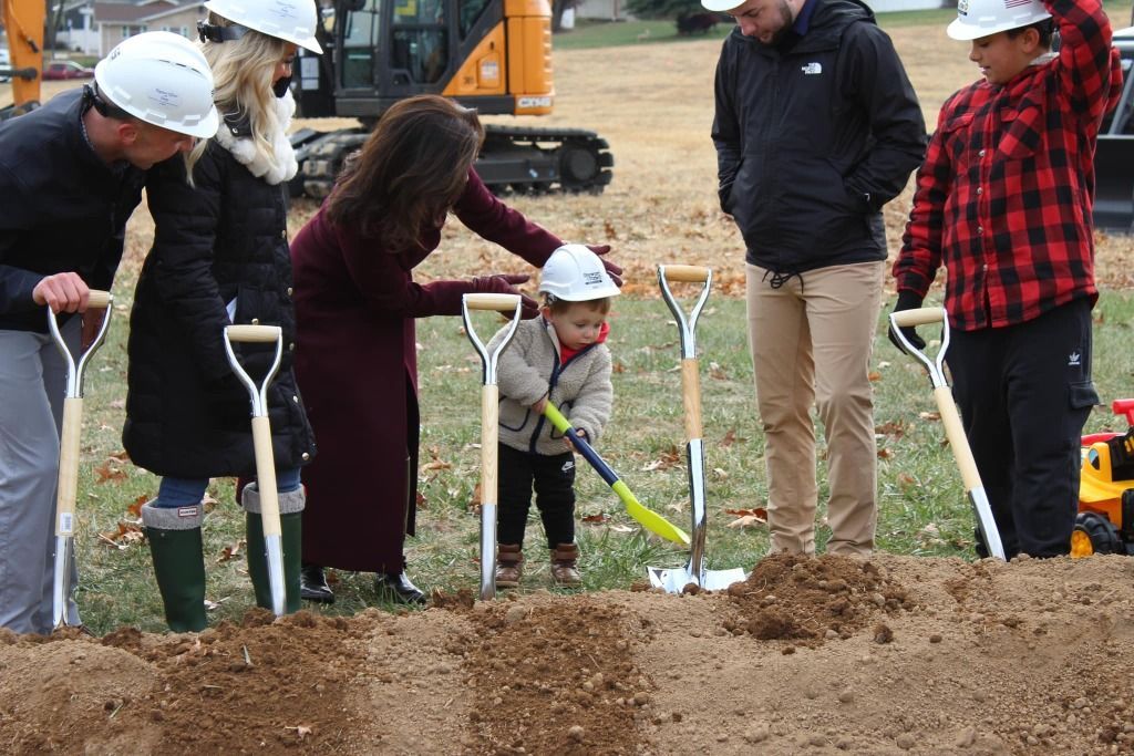 People with shovels, including a child, at a ground-breaking ceremony.