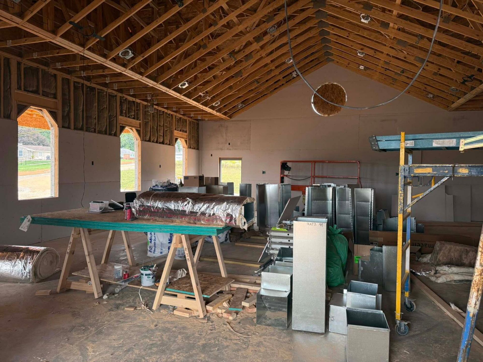 Interior of a building under construction, showing exposed wooden beams, drywall, and HVAC ductwork.