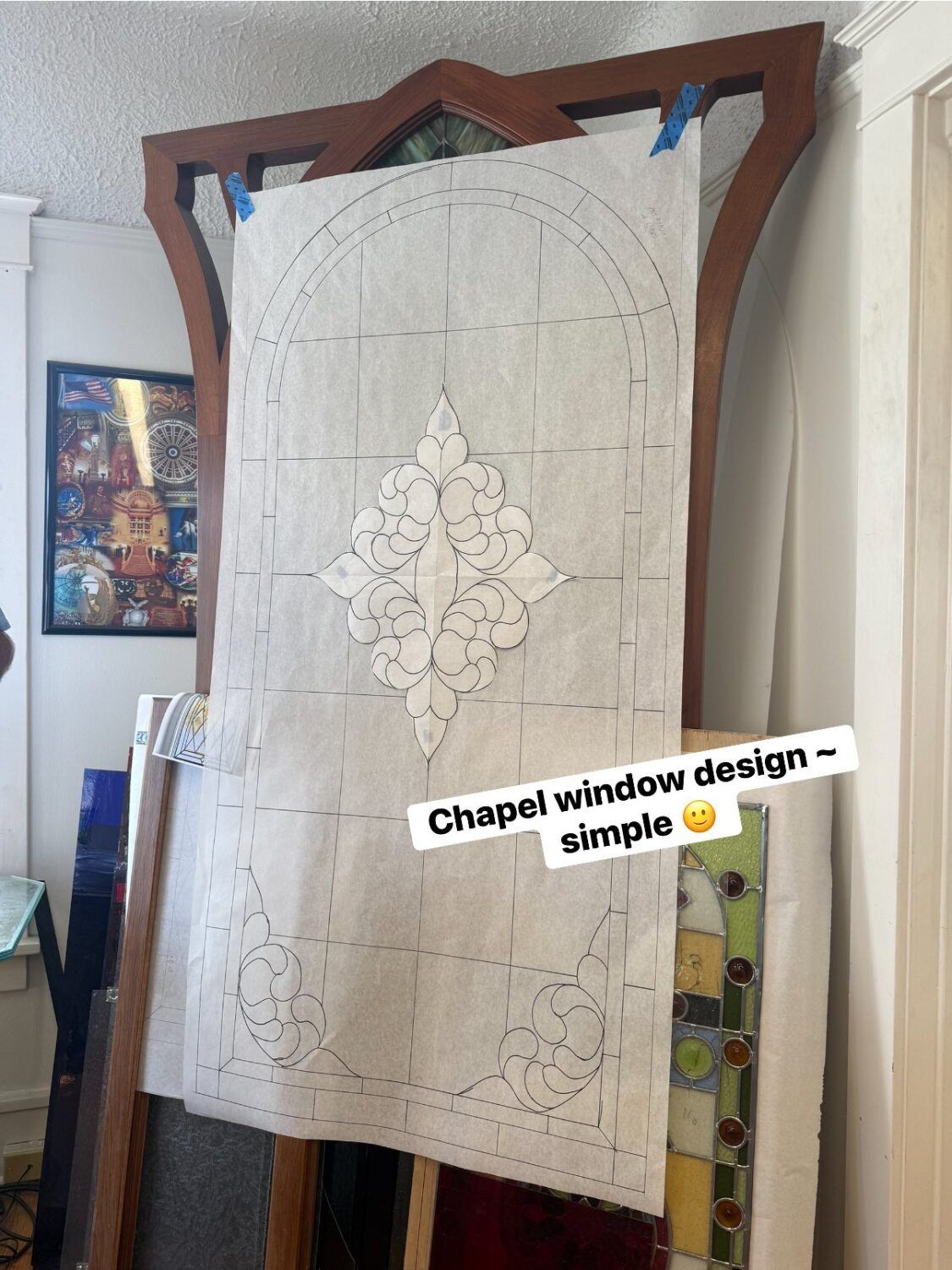 Design for a chapel window, drawn on paper, taped to a wooden frame.