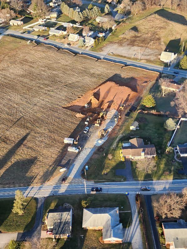 Aerial view of construction site with equipment on a road next to a field.