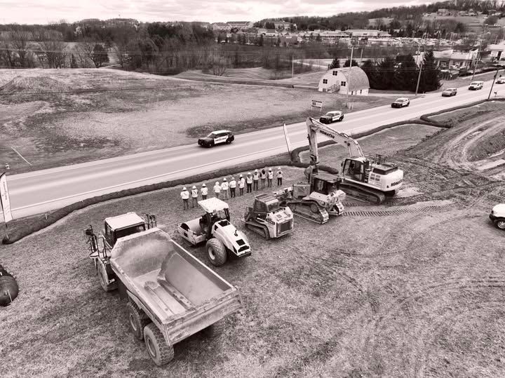 Construction site with heavy machinery and a group of people standing near a road.