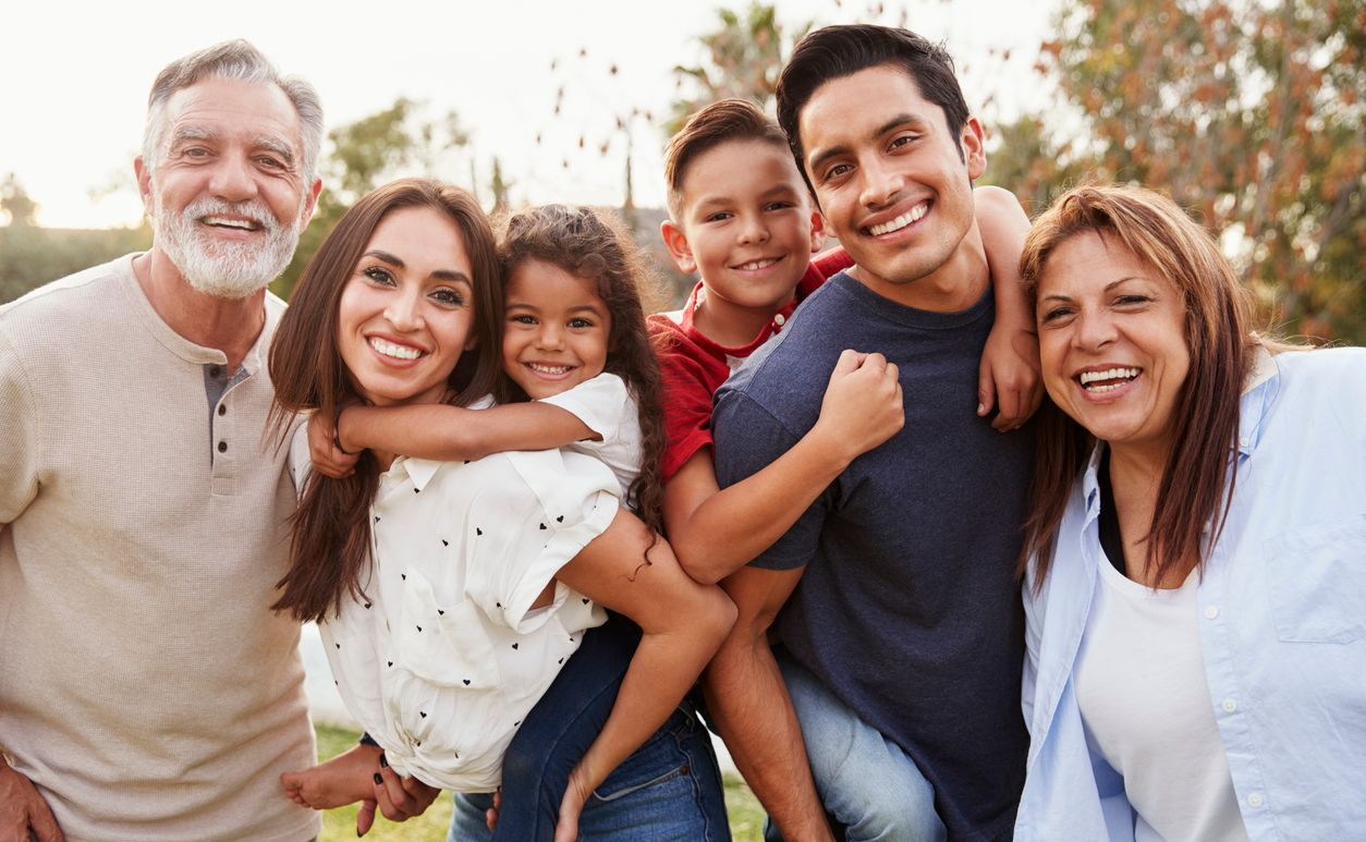 A young man is sitting at a table with his hands on his forehead.