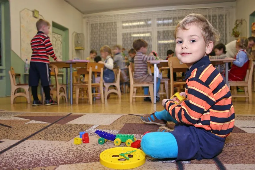 A young boy is sitting on the floor playing with toys in a classroom.