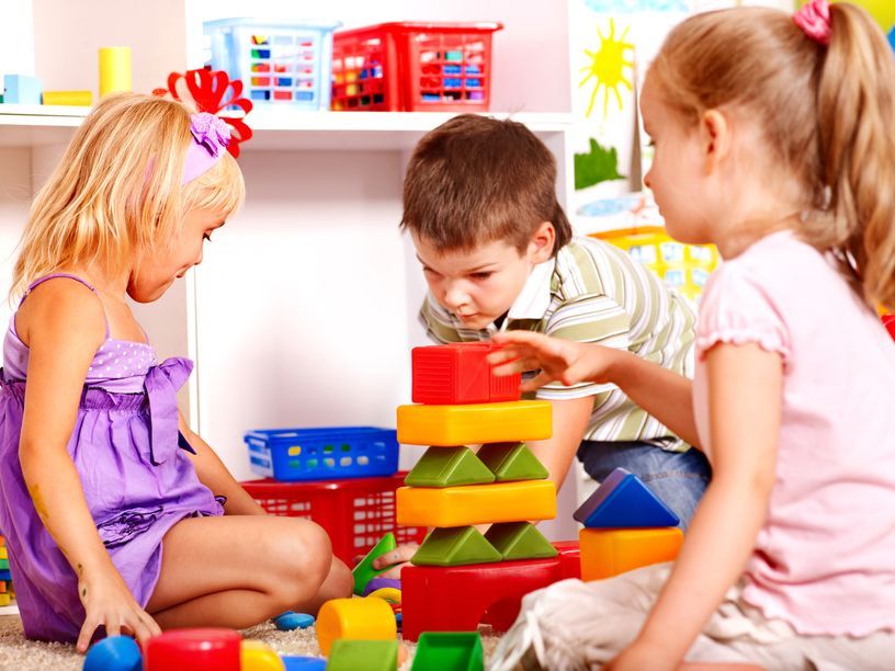 A group of children are playing with blocks on the floor.