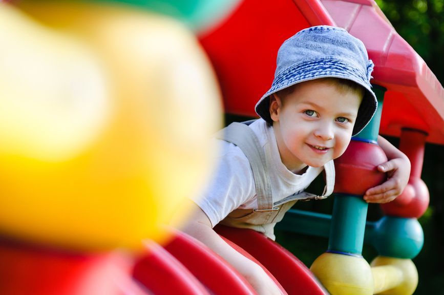 A young boy is playing on a slide at a playground.