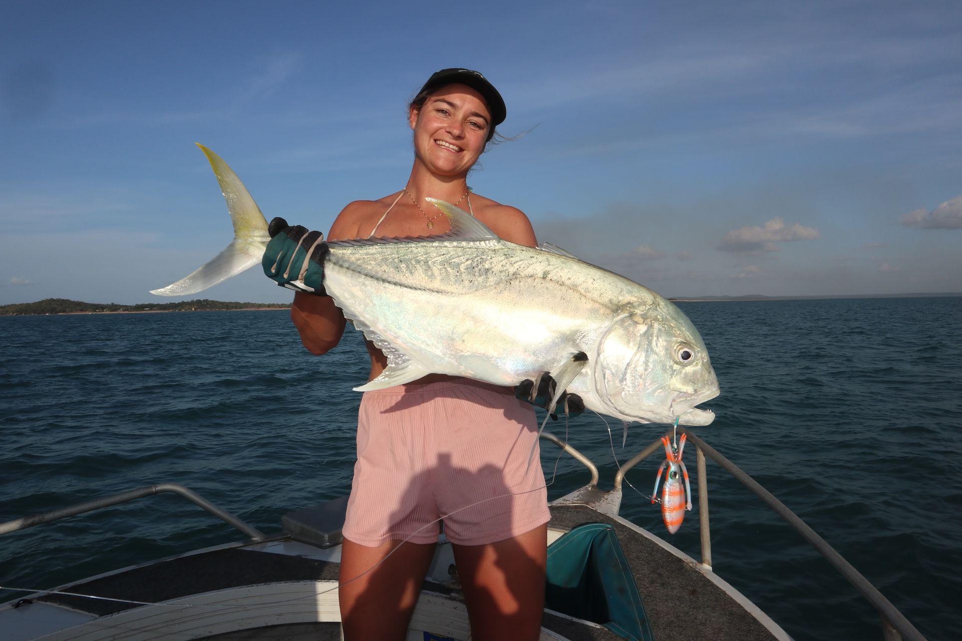 A woman is standing on a boat holding a large fish.