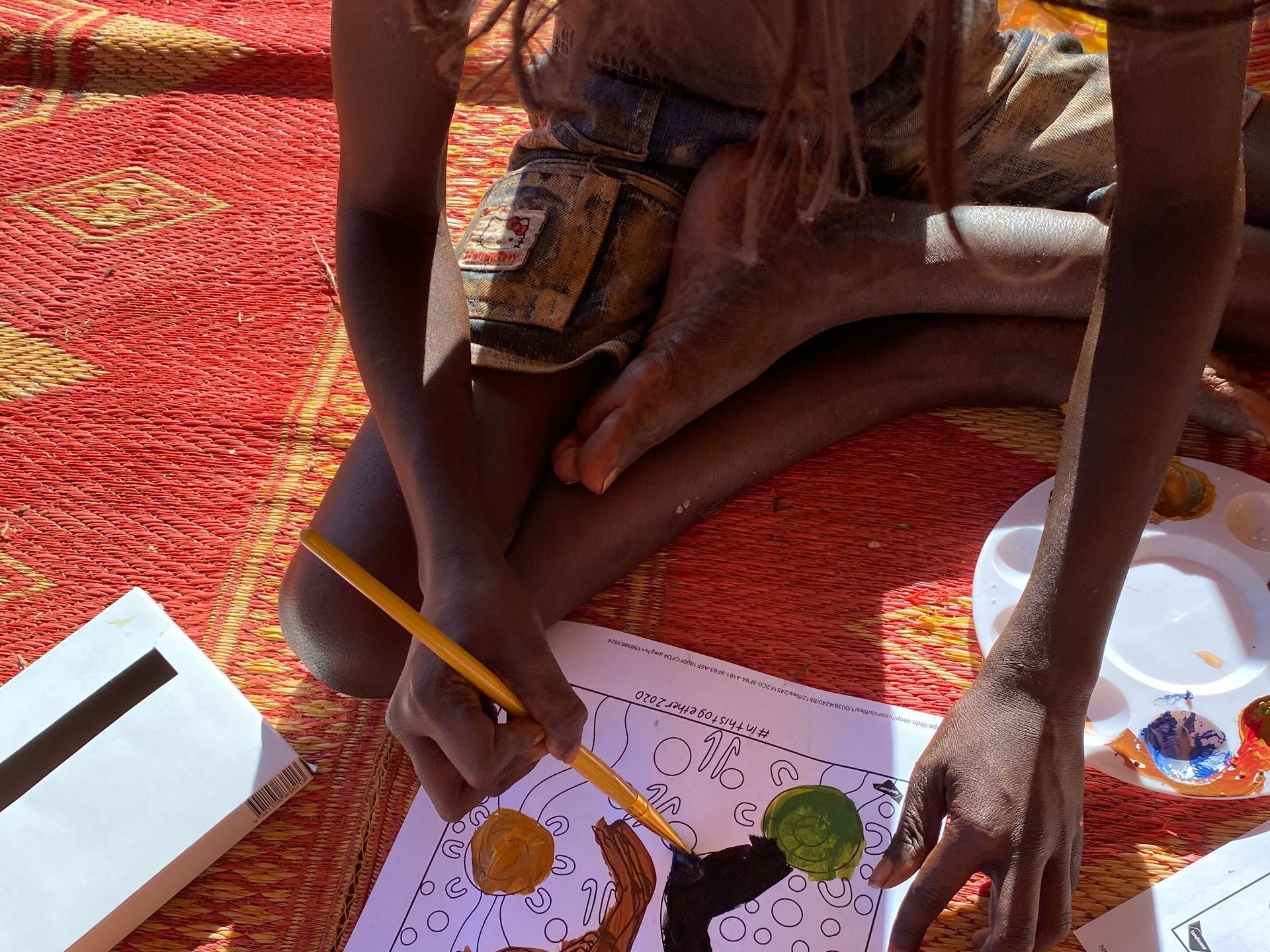 A child is sitting on the floor drawing with a pencil