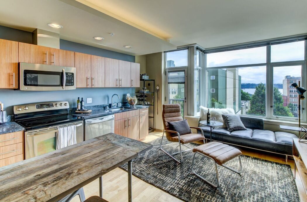 Open-concept kitchen and living area with stainless steel appliances and large windows.