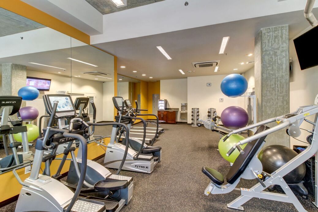 Indoor community gym with cardio machines, weight equipment, and stability balls.