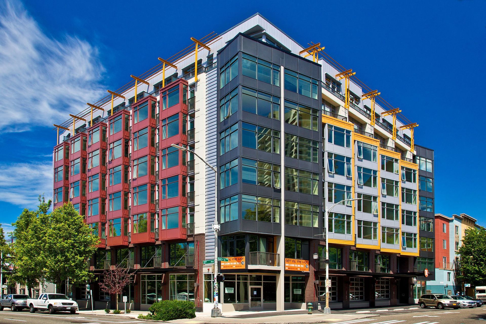 Exterior view of a modern, color-blocked apartment building with large windows on a sunny day.