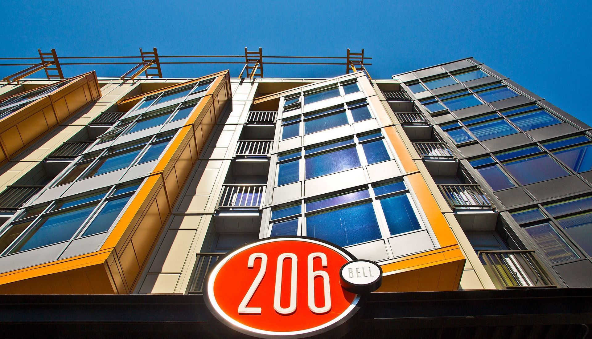 Low-angle view of a modern apartment building exterior with balconies and orange trim.