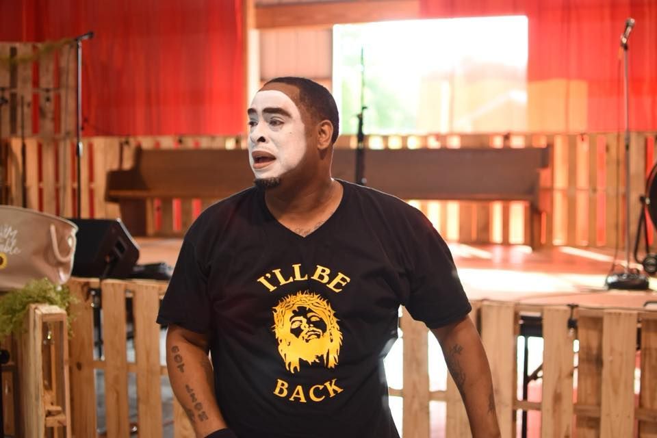 A person in mime makeup and a black 