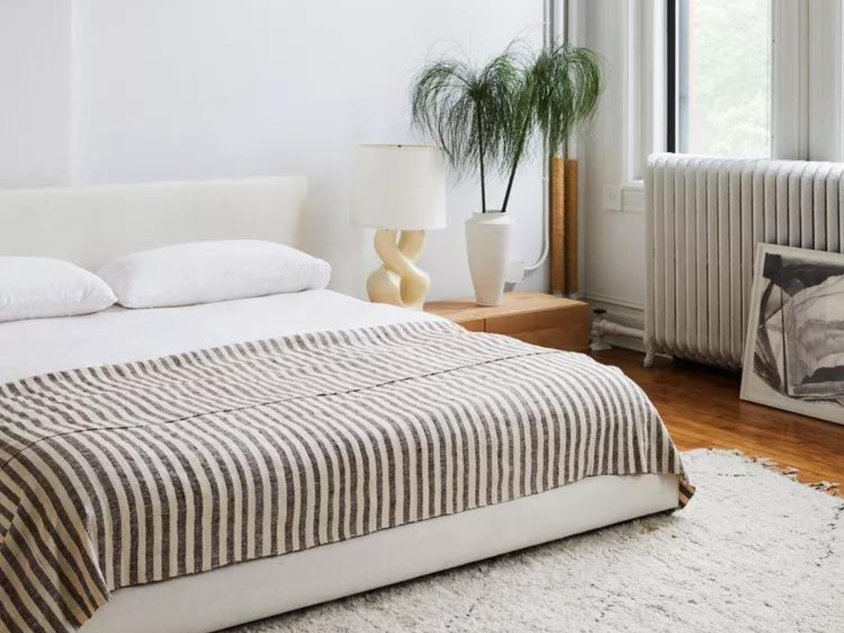 A bedroom with a bed , a lamp , and a plant.