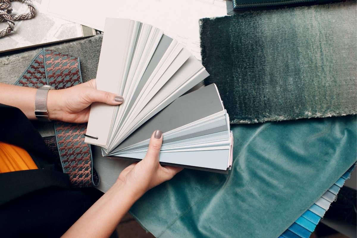 A woman is holding a fan of fabric samples in her hands.