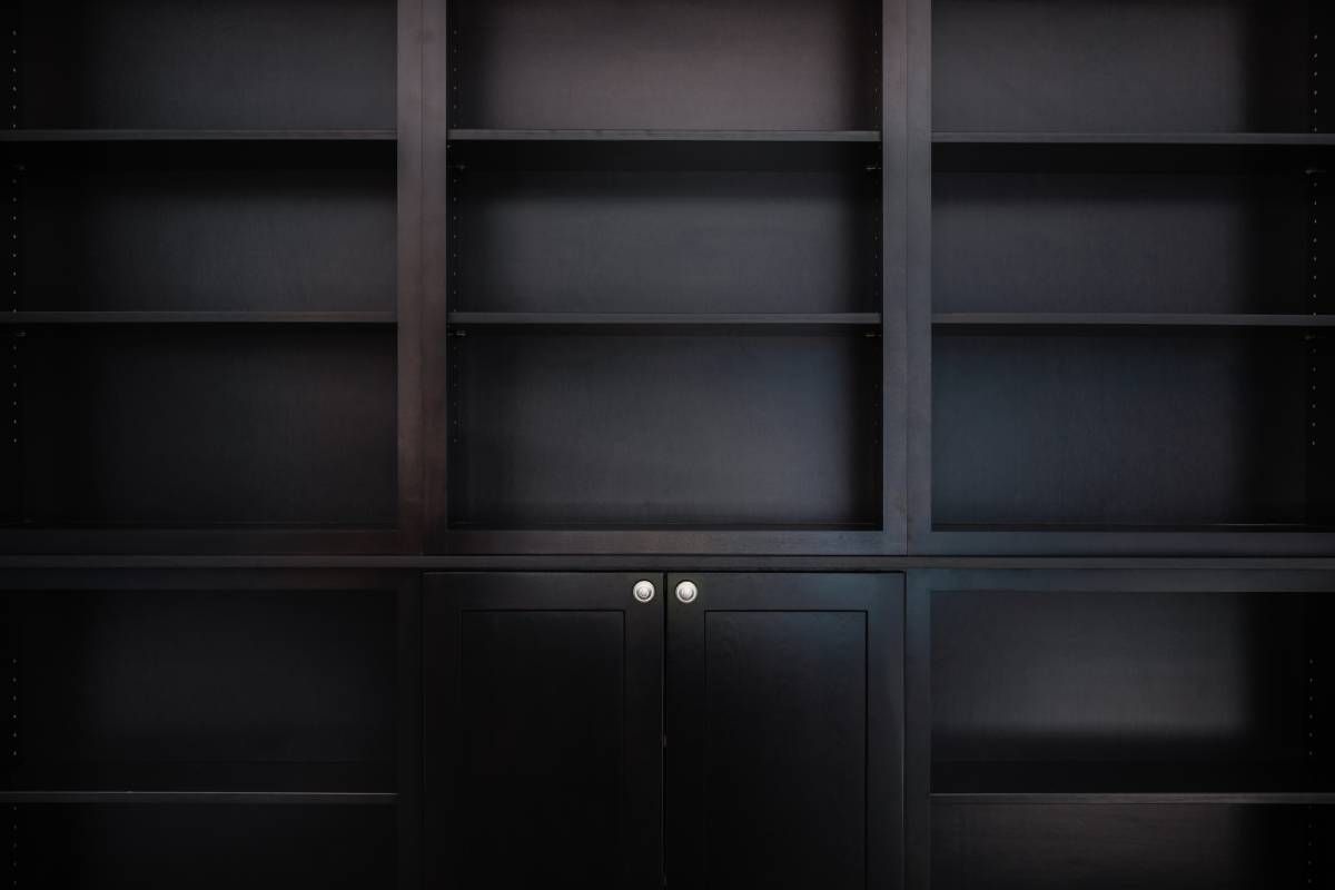 A wall of custom black shelves and cabinets in a dark room