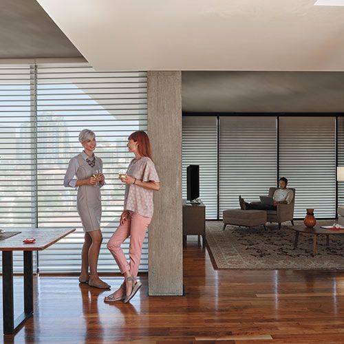 Two women are standing next to each other in a living room with custom furniture