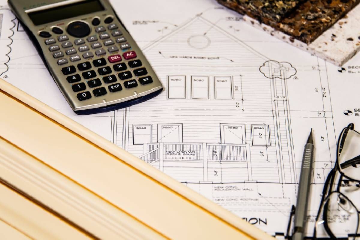 A calculator is sitting on top of a blueprint of a house.