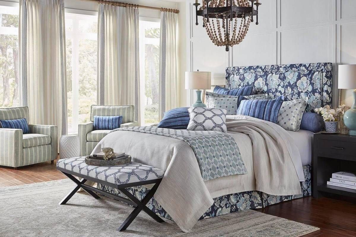 A bedroom with a bed , chair , nightstand , bench and chandelier from Heritage Design