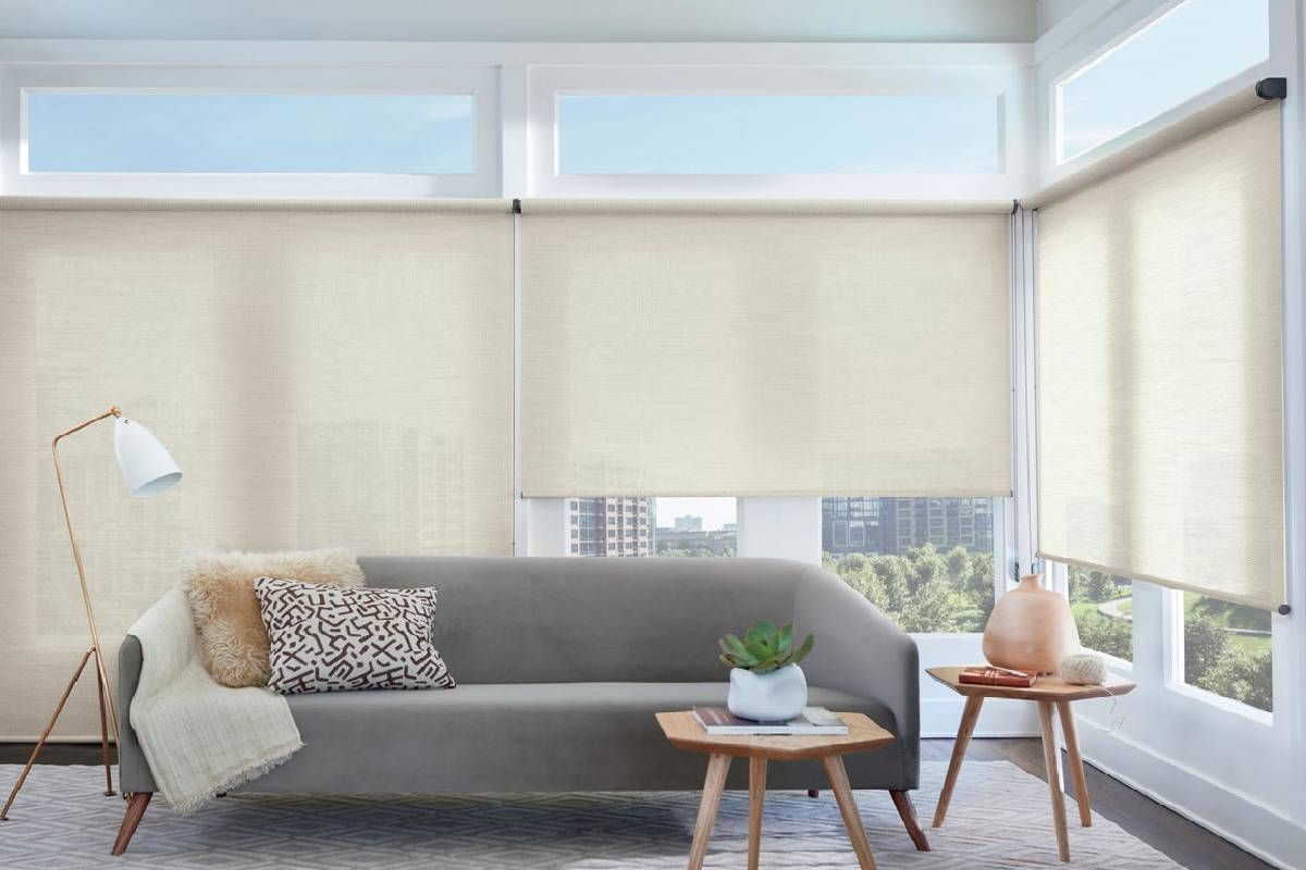 A living room with a couch , two tables and Hunter Douglas woven wood shades