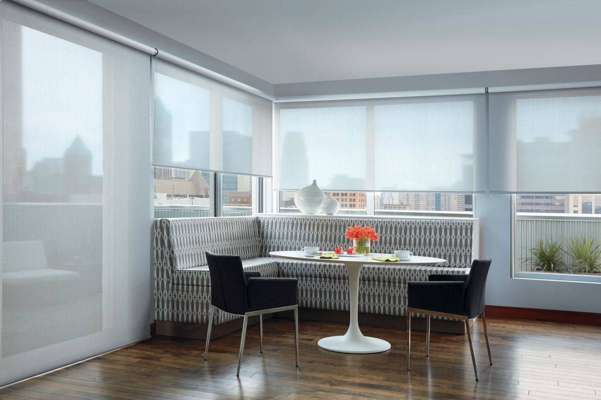 A living room with a table and chairs and custom roller shades on the windows