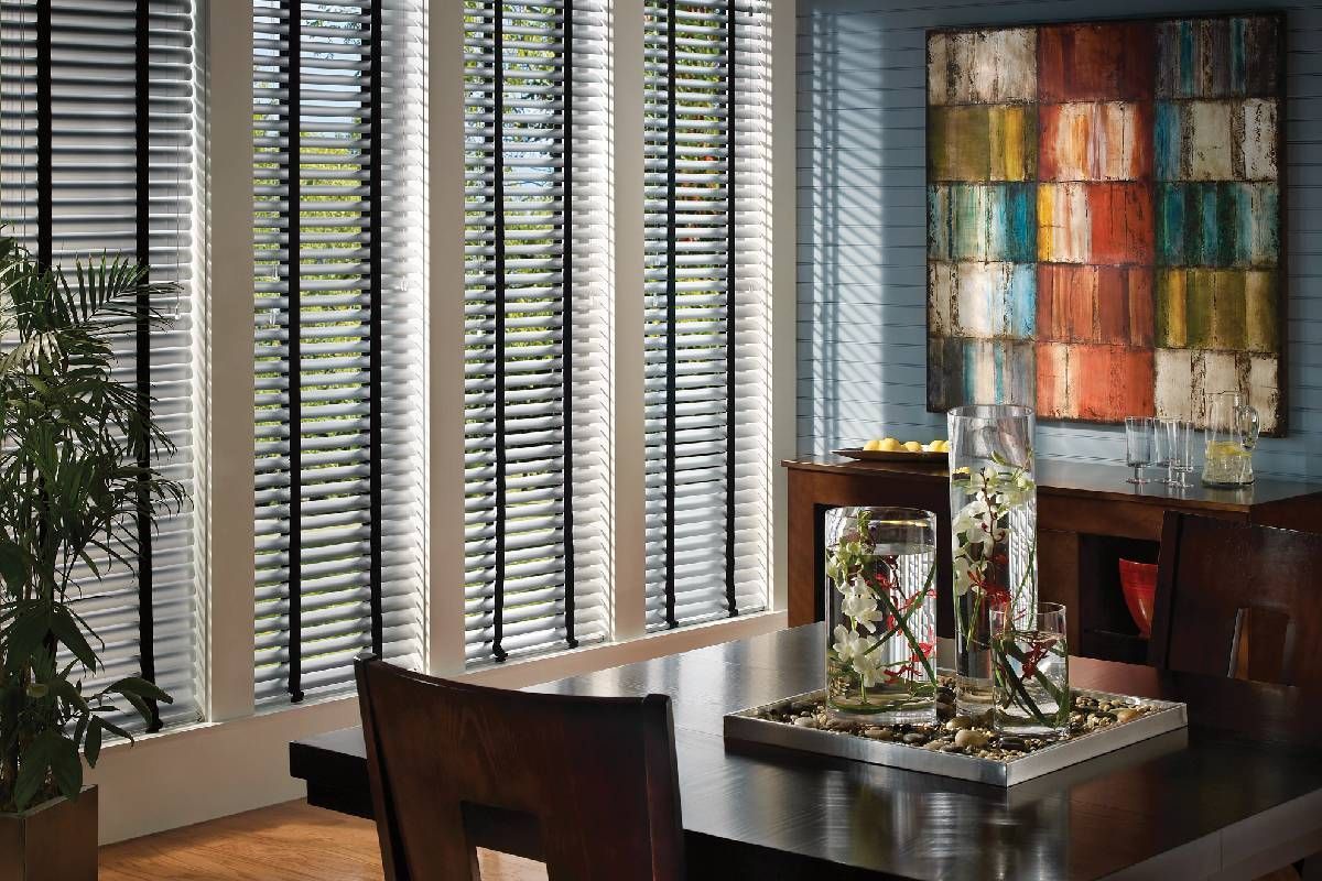 A dining room with a table and chairs and  Parkland wood blinds on the windows.