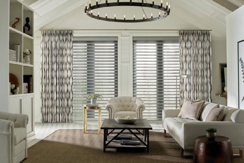 A living room with a couch , chair , coffee table and custom curtains