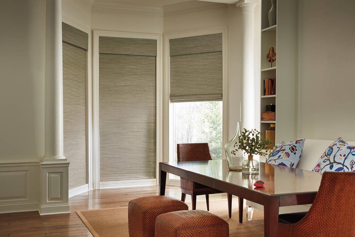 A living room with a couch , table , chairs and Hunter Douglas wood shades