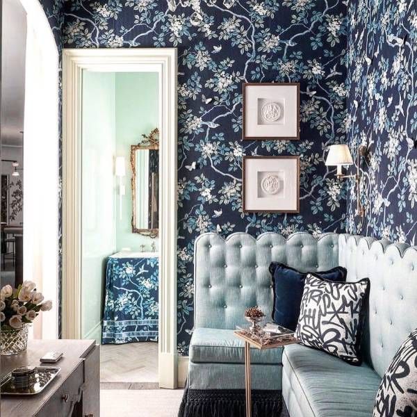 A living room with blue floral wallpaper and a couch