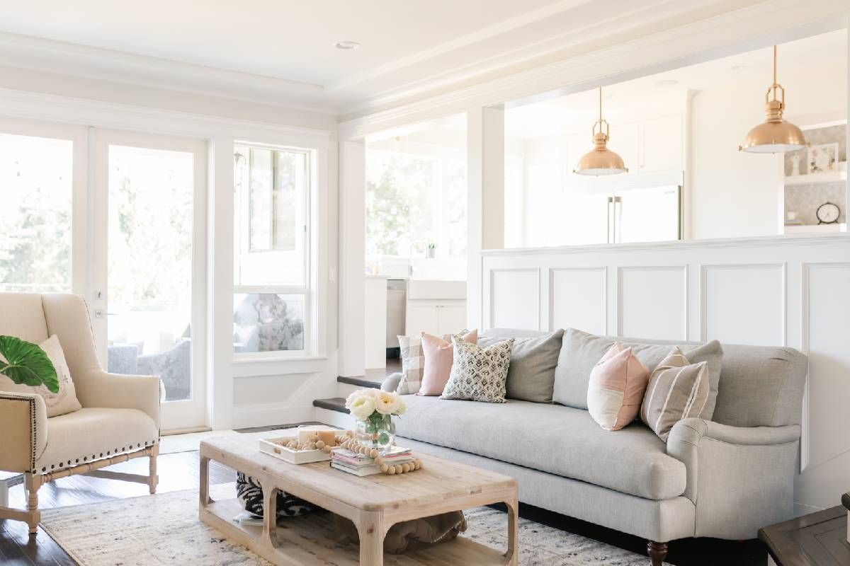 A living room with a couch , chair , coffee table and lots of Hunter Douglas windows.