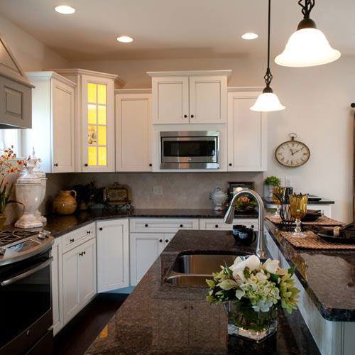 A kitchen with white cabinets and a clock on the wall.