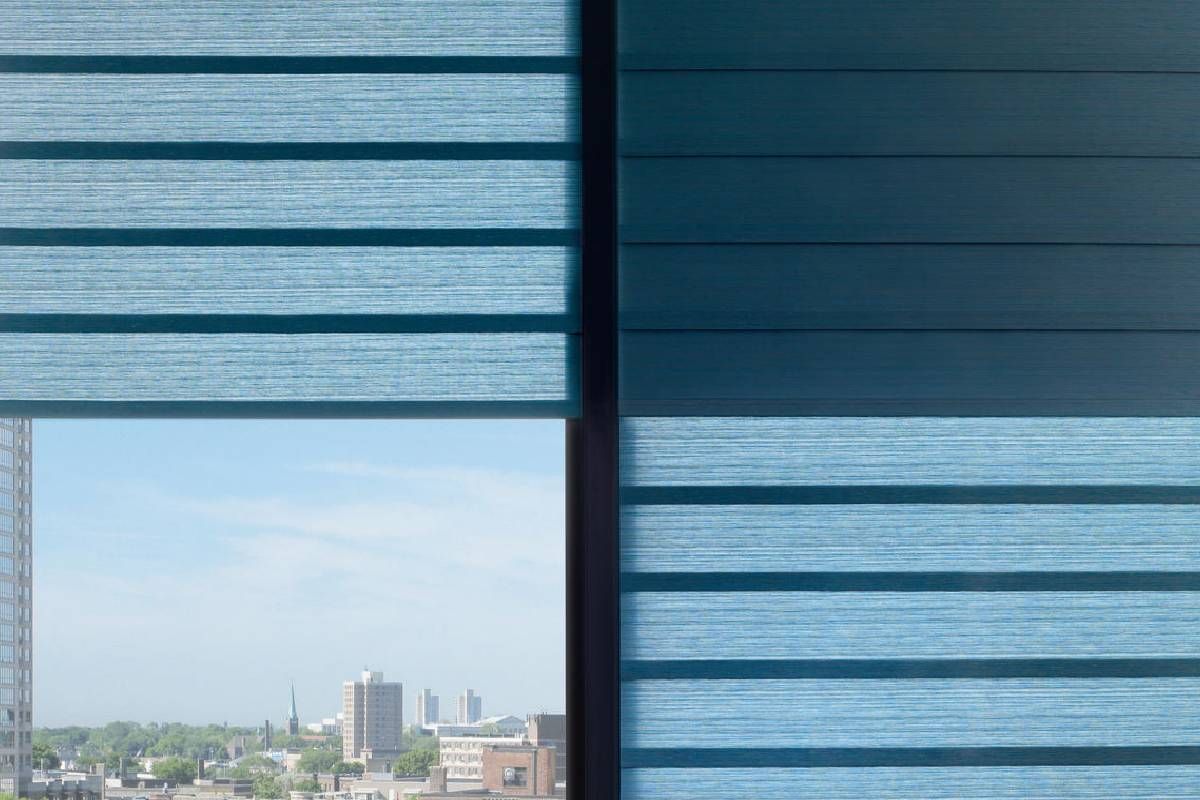 A Hunter Douglas treated window with blue blinds and a view of a city.