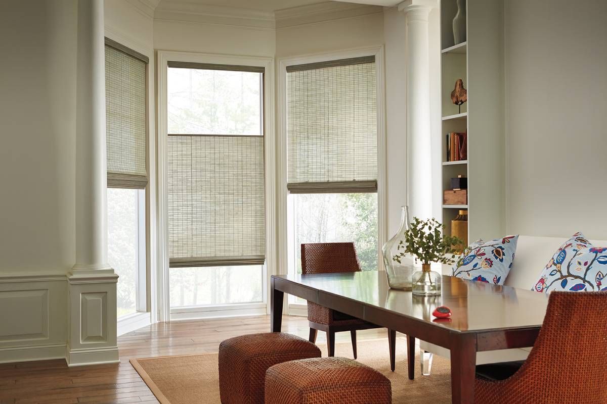 A living room with a table and chairs and a Hunter Douglas treated window with roman shades.