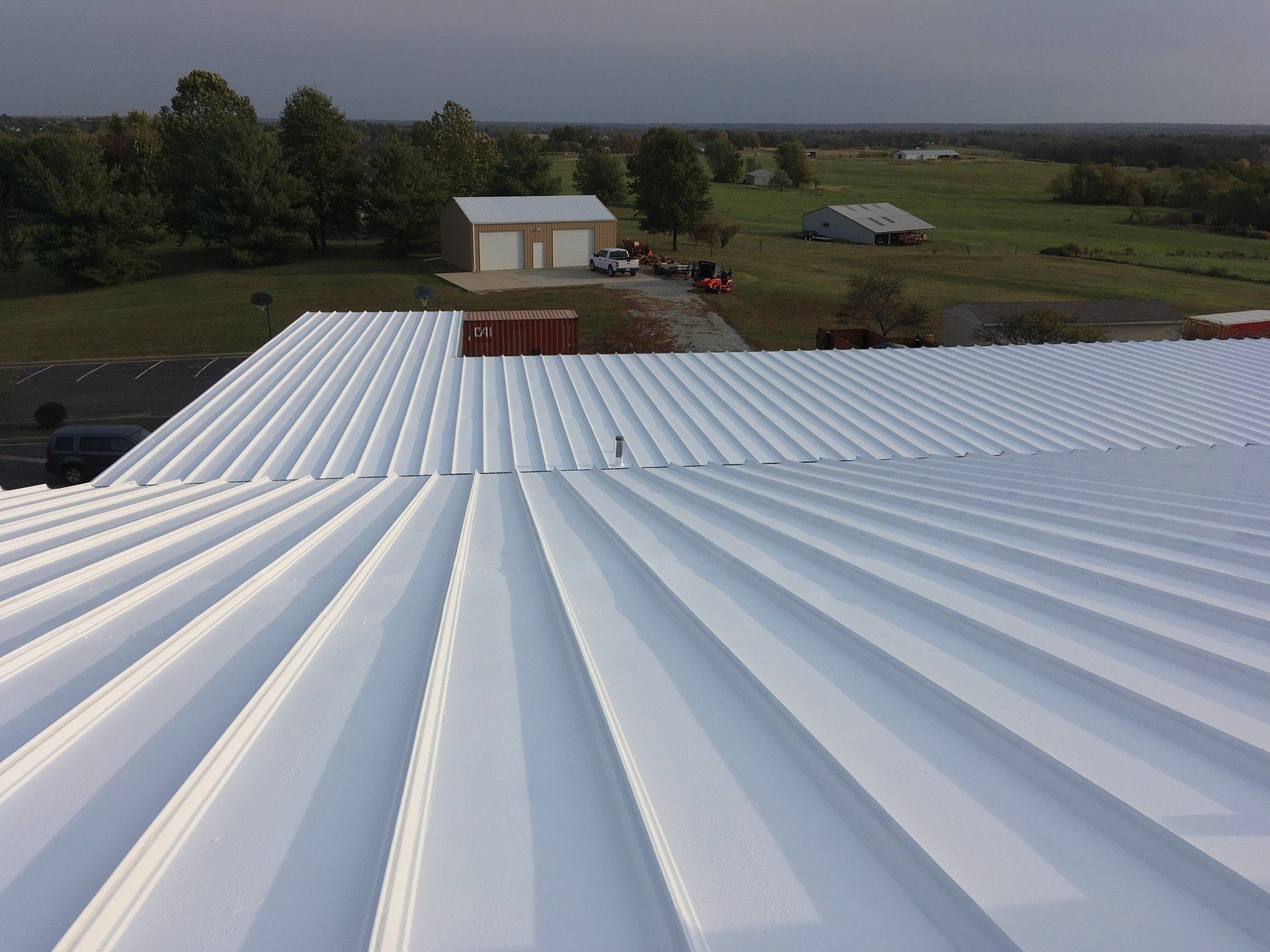 An aerial view of a white roof with a house in the background