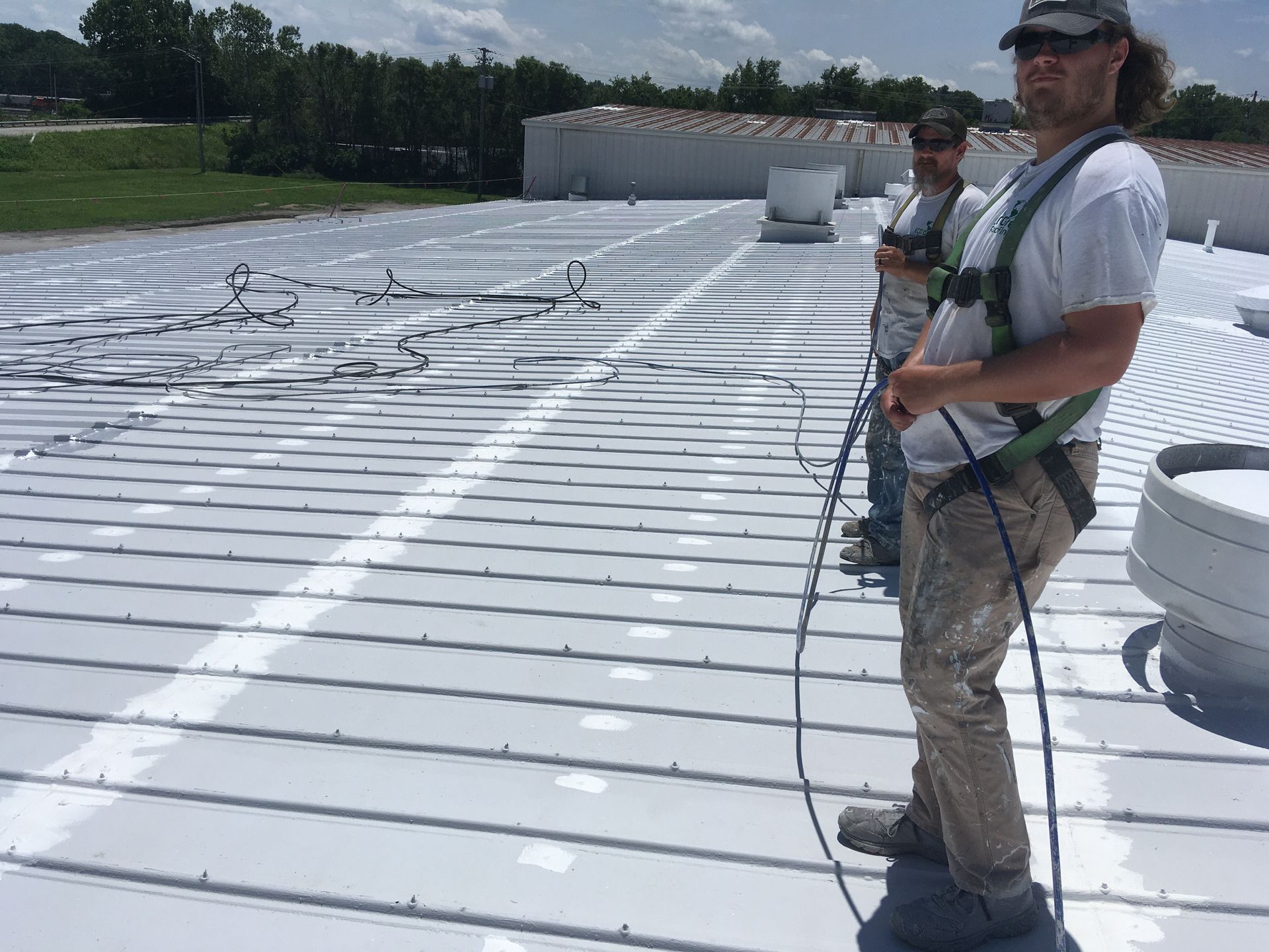 Two men are standing on top of a white roof.