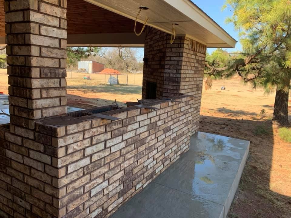 Brick outdoor serving window on a house with a concrete patio and yard beyond