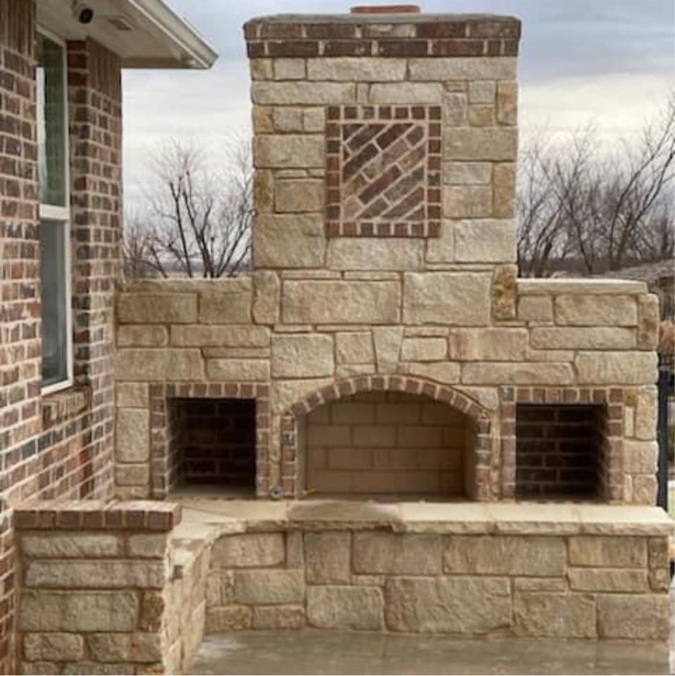 Stone outdoor fireplace with brick accents and built-in bench seating on a patio