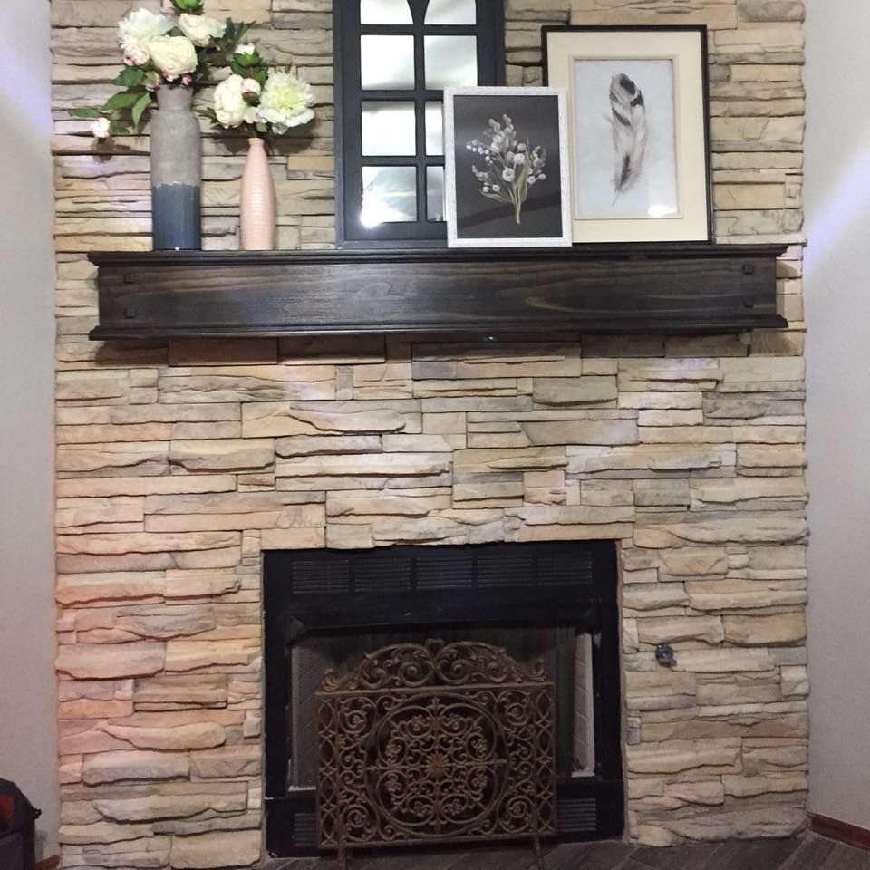 Stone fireplace with dark mantel, floral vases, and framed artwork above the hearth.