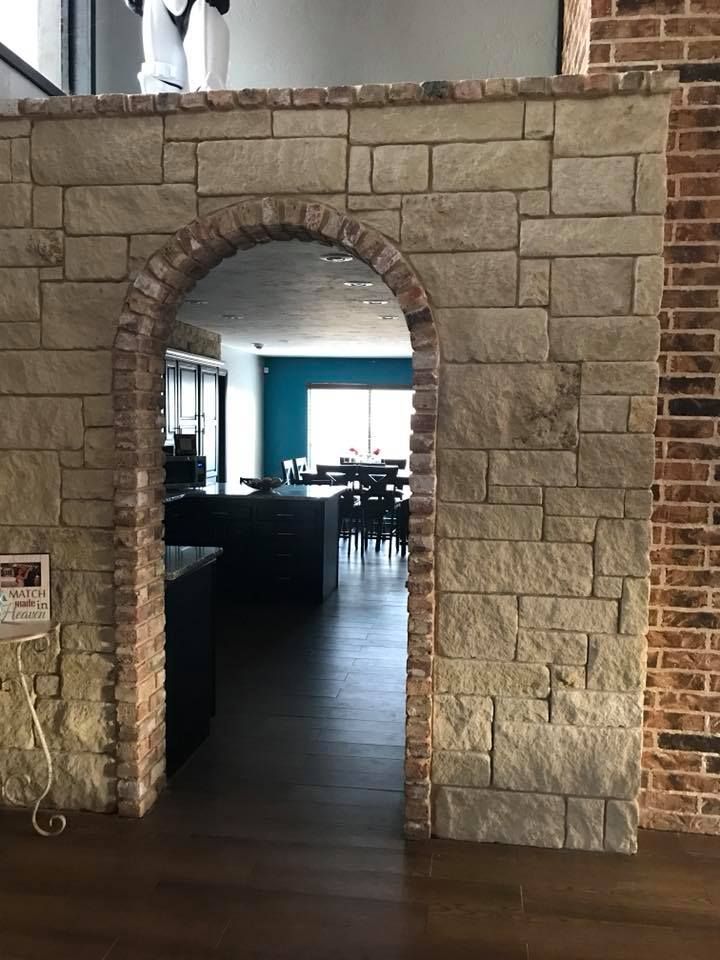 Stone archway entrance into a dim restaurant with dark wood floors and blue walls visible inside