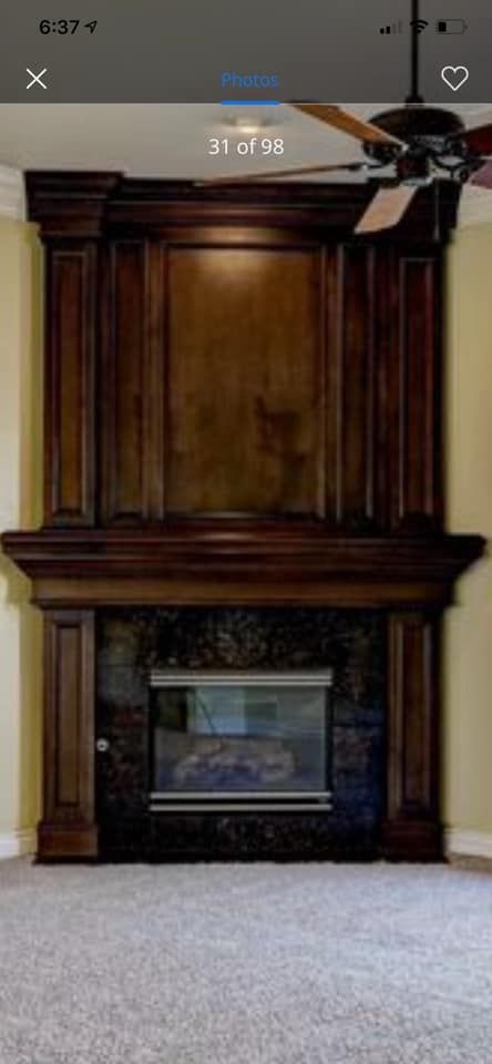 Dark wood fireplace mantel with built-in cabinets in a carpeted room