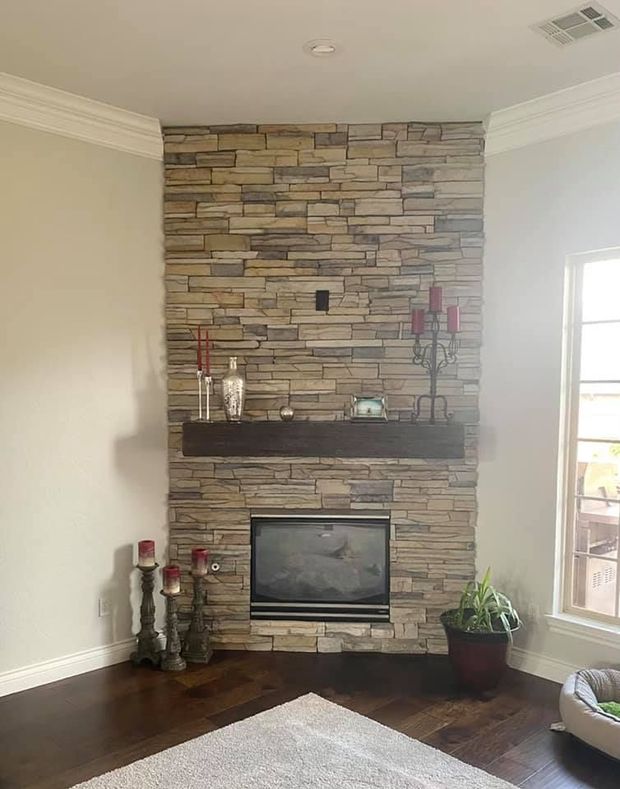Living room with stone fireplace, dark wood floors, and a large window on the right
