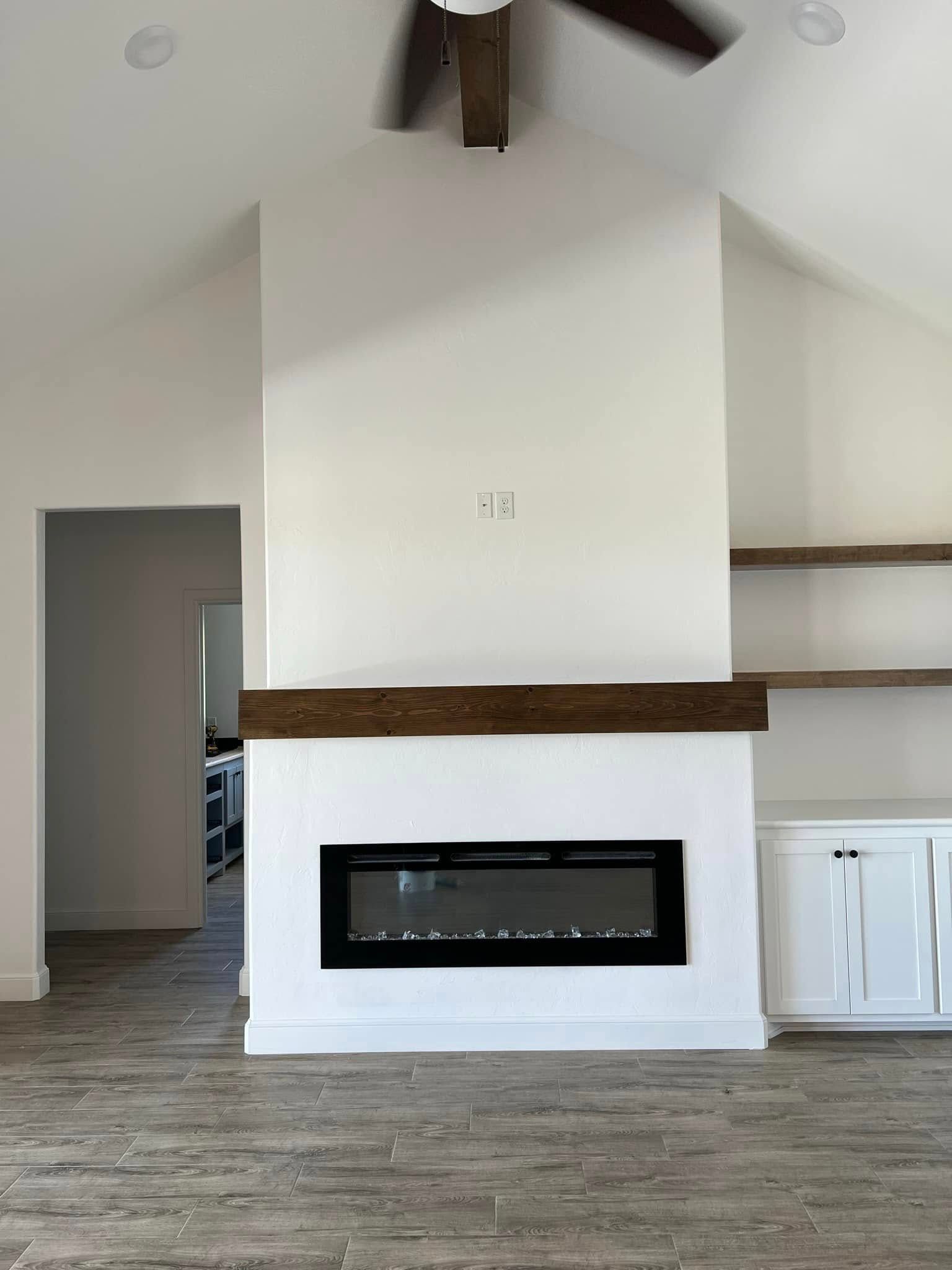 Modern living room with white walls, wood beams, a fireplace, and built-in shelves.