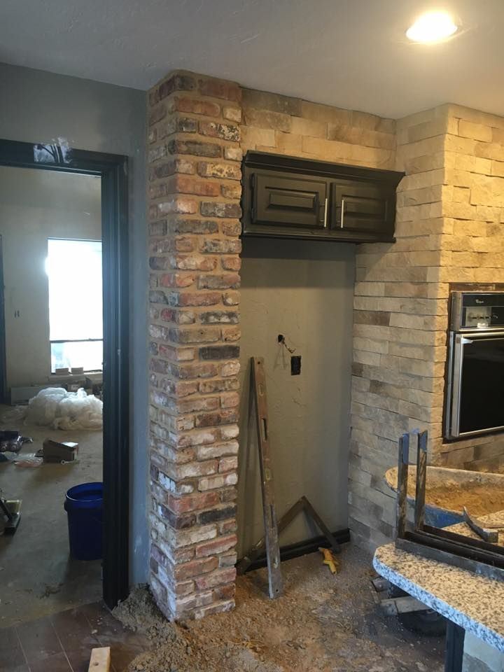 Kitchen nook with exposed brick walls, a dark cabinet, and a granite countertop in a partially finished room