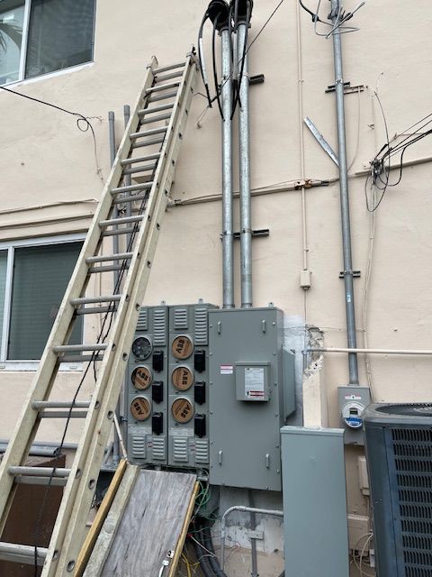 Ladder leaning against building with electrical equipment.