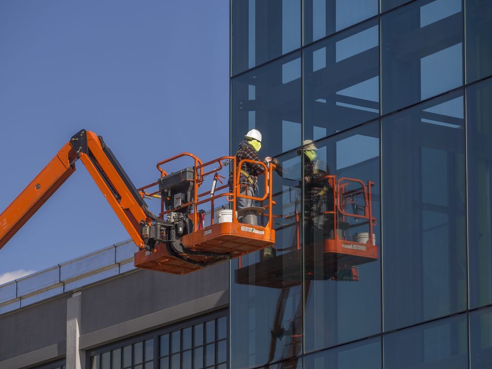 Two Workers in an Orange Lift Platform Cleaning the Glass — Crystal Clear In Glen Innes, NSW