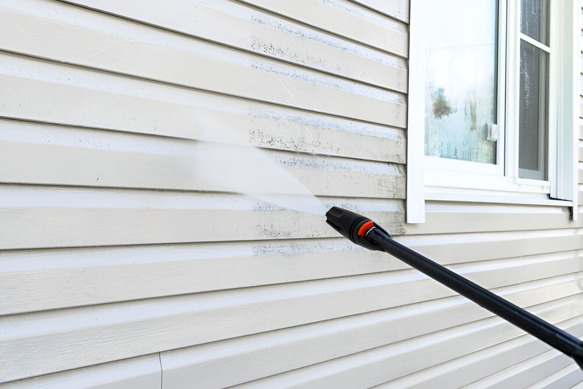 A Person Is Cleaning The Side Of A House With A High Pressure Washer — Crystal Clear In Armidale, NSW