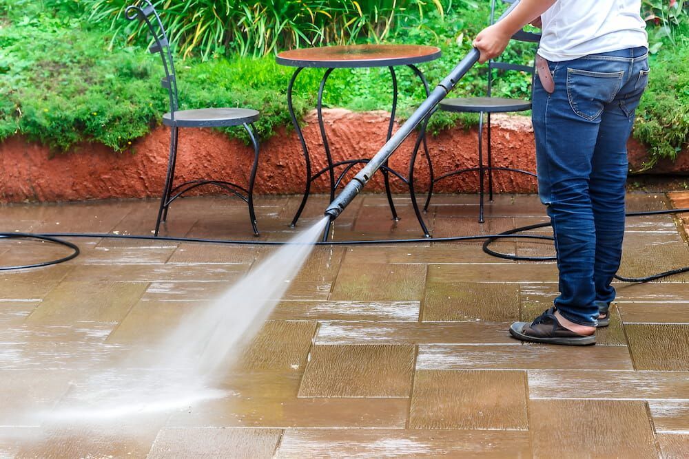 A Man Is Using A High Pressure Washer To Clean A Patio — Crystal Clear In Guyra, NSW